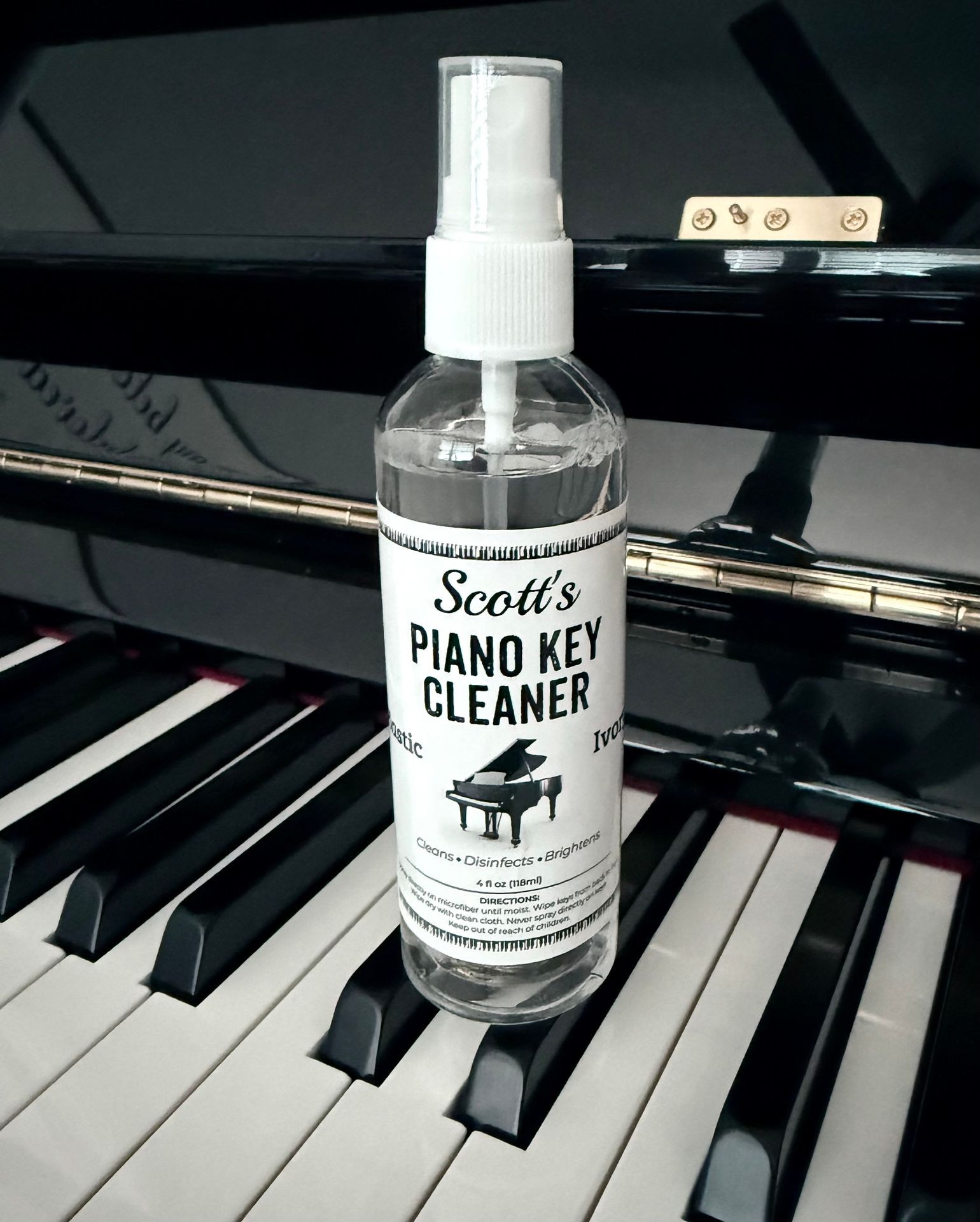 Bottle of piano key cleaner placed on a black and white piano keyboard.